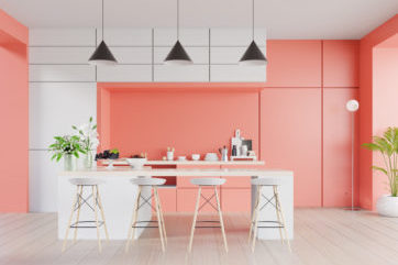 Coral and white coloured kitchen with island and bar stools