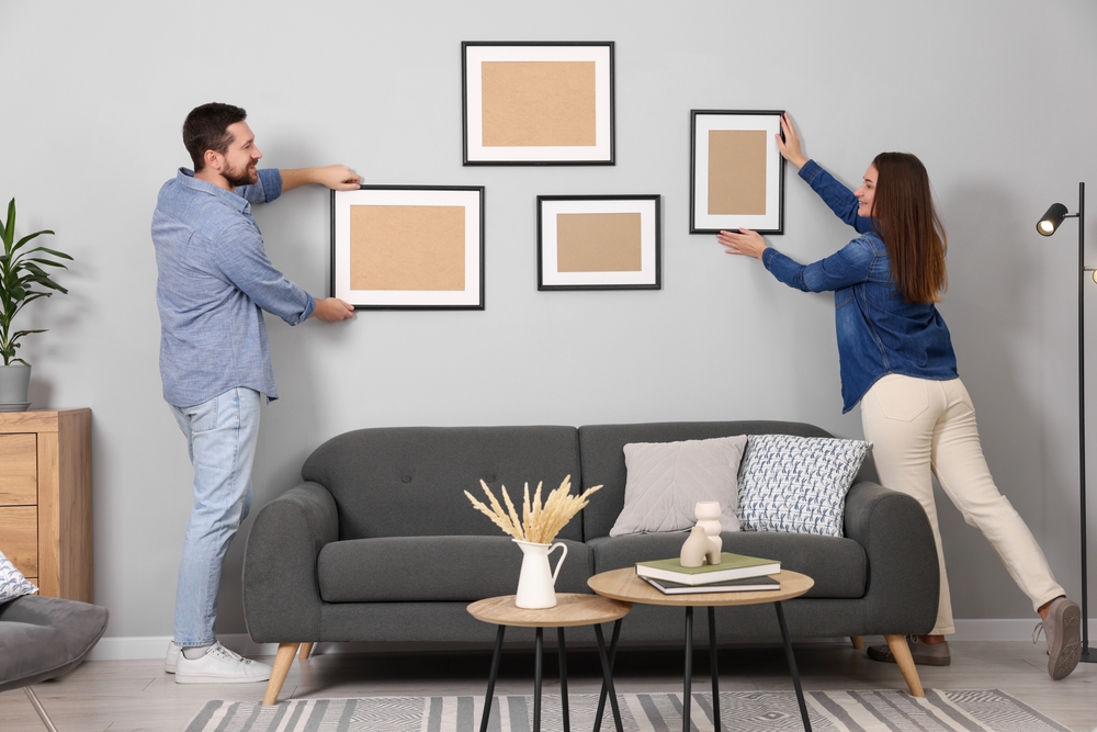 Man and woman hanging picture frames